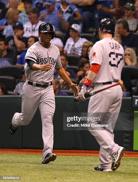 Xander Bogaerts and Mike Carp of the Boston Red Sox celebrate after Bogaerts scores in the ninth inning against the Tampa Bay Rays during Game Three...