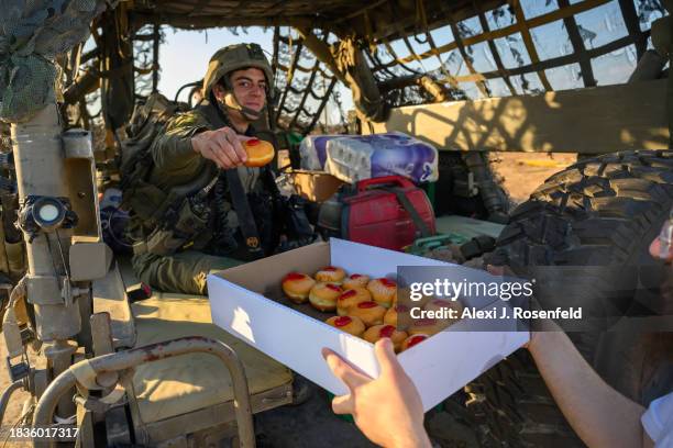 Volunteers hand sufganiot and hanukkiahs to soldiers the day before Hanukkah begins near the Gaza border on December 06, 2023 in Southern Israel....