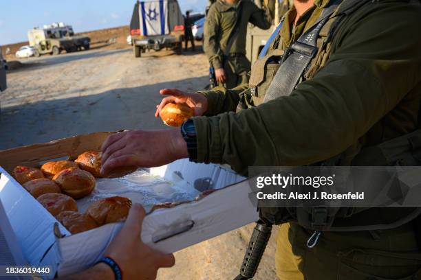 Volunteers hand sufganiot and hanukkiahs the day before Hanukkah begins near the Gaza border on December 06, 2023 in Southern Israel. Israel and...