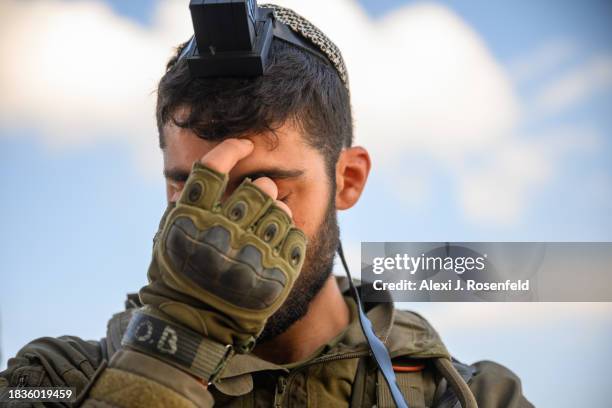 Soldier lays tefillin near the Gaza border on December 06, 2023 in Southern Israel. Israel and Hamas have resumed fighting after the end of a...