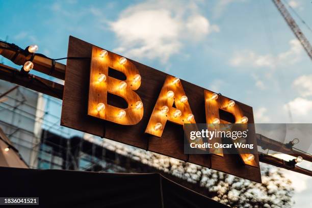 bar sign with illuminated light bulbs against blue sky - letrero de tienda fotografías e imágenes de stock