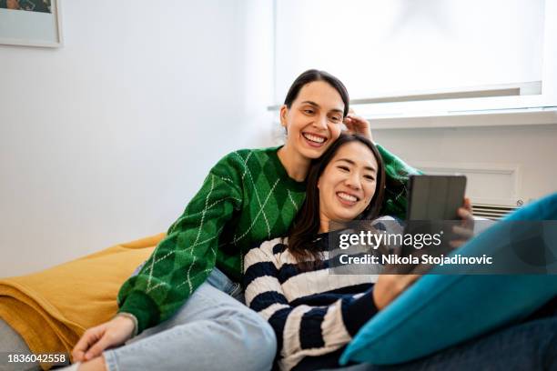 two beautiful women using their digital tablet on the couch - funny lesbian 個照片及圖片檔