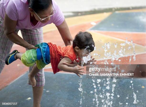 Young boy and his mother play in a water fountain on July 8, 2010 in New York City. Stifling heat is expected to continue in Philadelphia,...