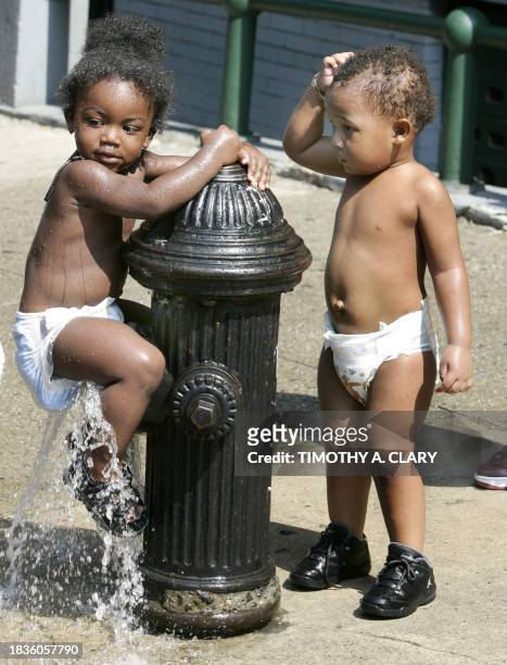 Emmanuel Ammonte and Boschi Pope, both two-years-old, play in the water from an open fire hydrant as young kids in Harlem try to beat the heat 01...