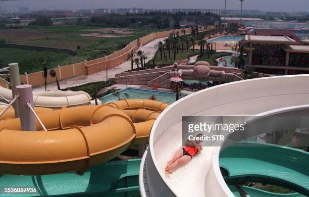 Woman slides down a shoot in a new Shanghai water park 21 July. The scorching summertime heat is driving many local people to the park, despite the...