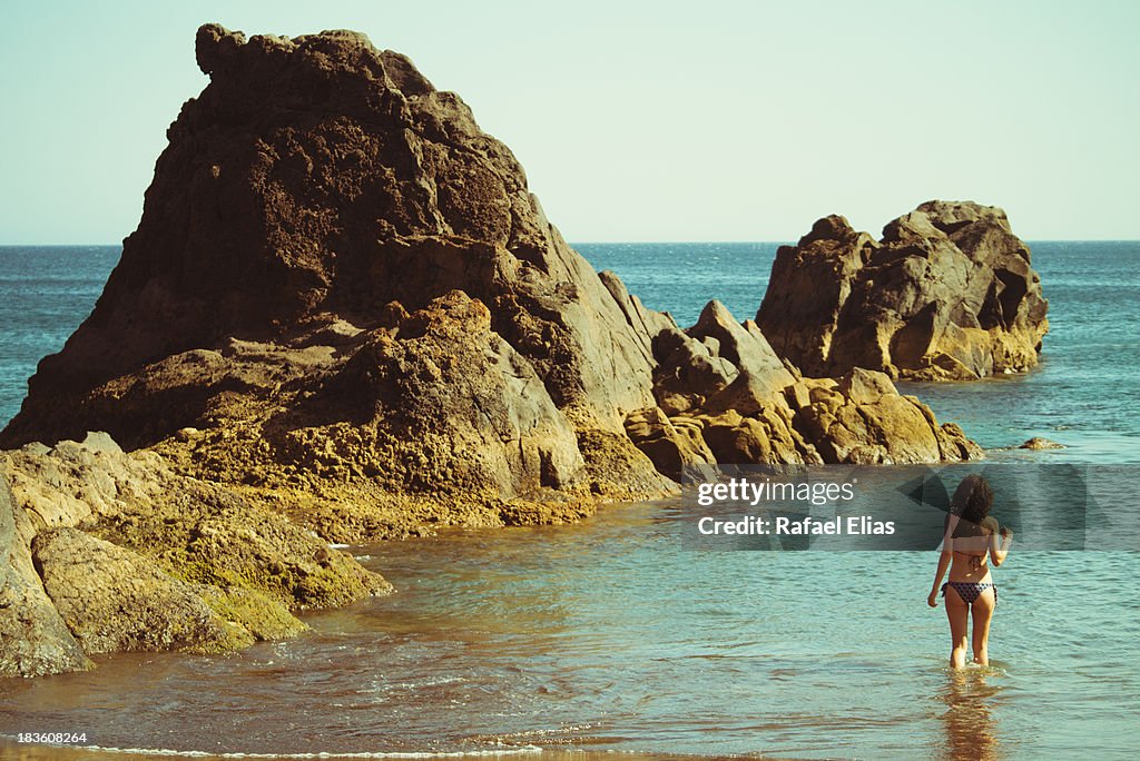 Young woman entering water at beach