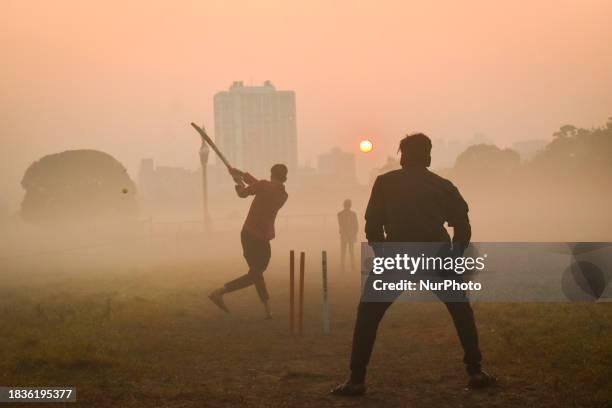 People are playing cricket on a foggy winter morning inside a ground in Kolkata, India, on December 10, 2023.