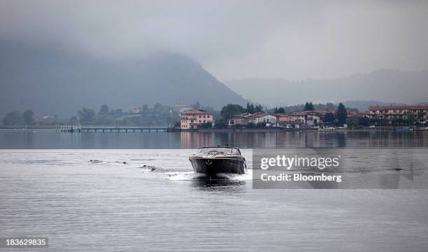 Residential properties sit on the bank of Lake Iseo as a Riva Rivarama Super luxury yacht, manufactured by Ferretti Group, returns to the company's...