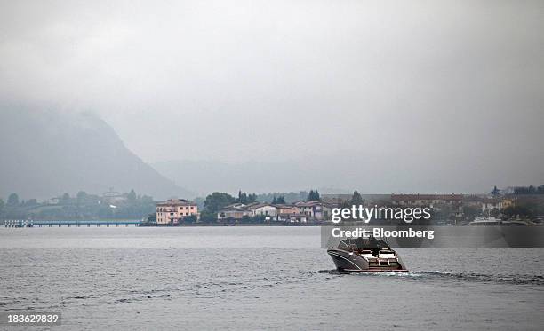 Residential properties sit on bank of Lake Iseo as a Riva Rivarama Super luxury yacht, manufactured by Ferretti Group, sits on the water near the...