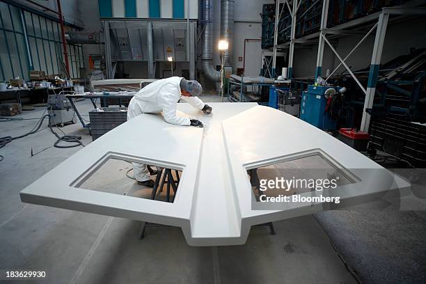 Shipwright uses a sander as he works on a molded fiberglass panel for a luxury yacht, manufactured by Ferretti Group, at the company's shipyard in...
