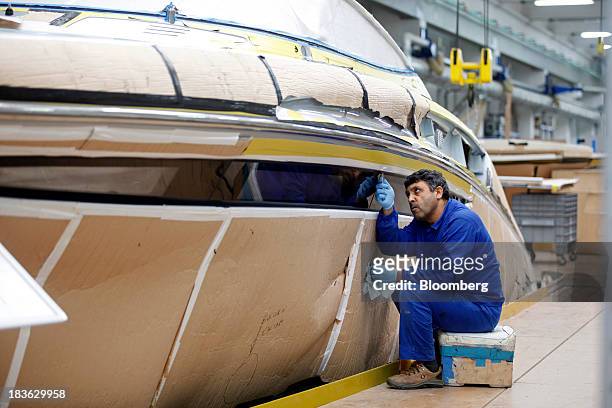 Shipwright works on the hull of a Riva Rivarama Super luxury yacht, manufactured by Ferretti Group, at the company's shipyard in Sarnico, Italy, on...