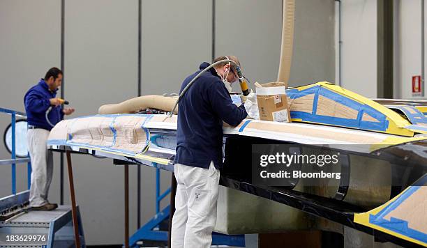 Shipwrights work on the deck panel of a Riva Rivarama Super luxury yacht, manufactured by Ferretti Group, at the company's shipyard in Sarnico,...