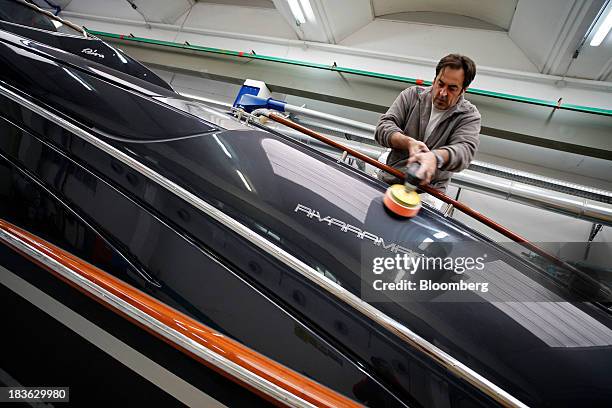 Shipwright polishes the decking of a Riva Rivarama Super luxury yacht, manufactured by Ferretti Group, at the company's shipyard in Sarnico, Italy,...