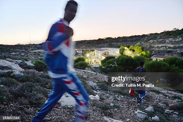 Immigrants walk outside of the temporary shelter Center where they are detained after their arrival in the island on October 8, 2013 in Lampedusa,...