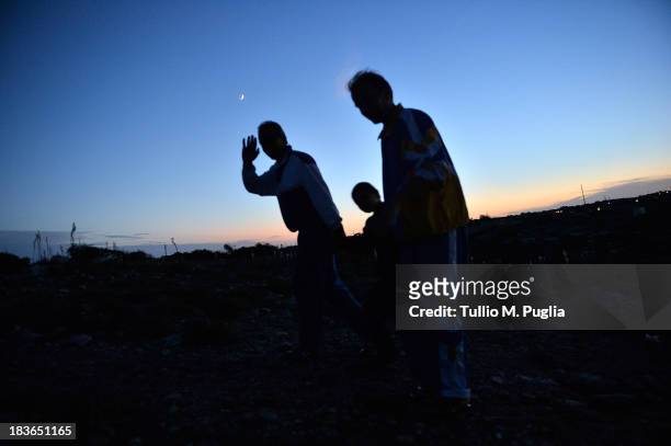 Immigrants walk outside of the temporary shelter Center where they are detained after their arrival in the island on October 8, 2013 in Lampedusa,...