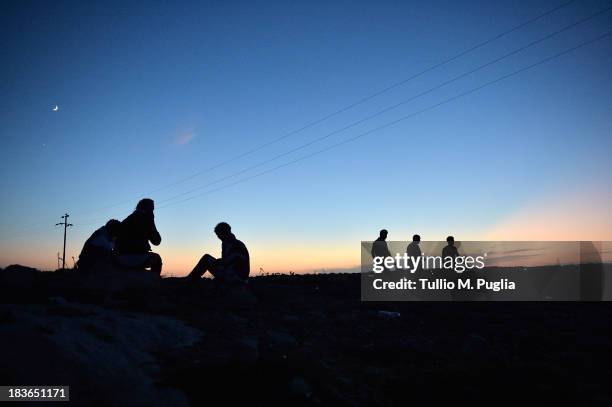 Immigrants walk outside of the temporary shelter Center where they are detained after their arrival in the island on October 8, 2013 in Lampedusa,...