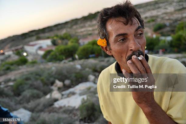 An immigrants smokes outside of the temporary shelter Center where they are detained after their arrival in the island on October 8, 2013 in...