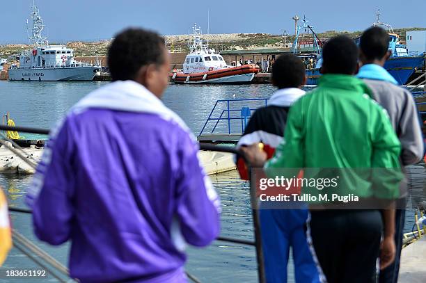 Survivors of the shipwreck of immigrants off the Italian coast stand near the water of Lampedusa on October 8, 2013 in Lampedusa, Italy. The search...