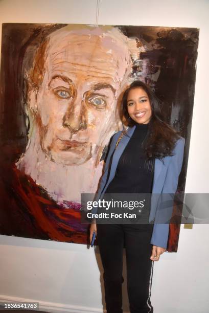 Miss France 2020 Clemence Botino poses with a portrait of Vladimir Cosma during "Immortels" Petra Marianne Marian's preview at Romanian Cultural...