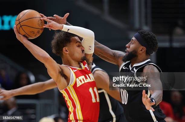 Royce O'Neale of the Brooklyn Nets defends against Trae Young of the Atlanta Hawks during the third quarter at State Farm Arena on December 06, 2023...