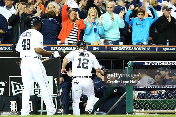 Andy Dirks of the Detroit Tigers celebrates with teammates in the dugout after scoring on a single by Jose Iglesias in the seventh inning against the...