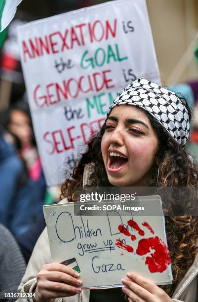 Protester holds a placard saying 'Children don't Grow Up In Gaza' with a fake bloody handprint. Thousands of people come together to call for a full...