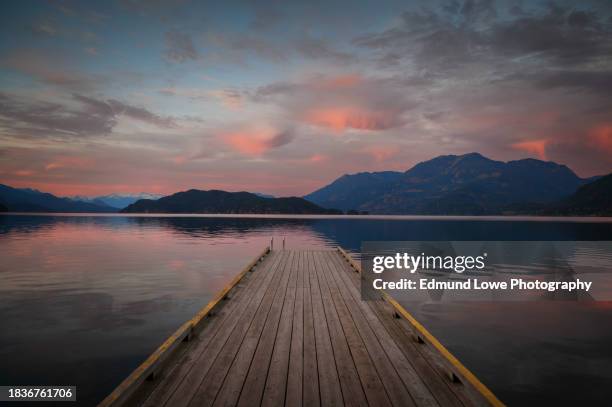 sunset with long pier leading out into water. - long jetty stock pictures, royalty-free photos & images