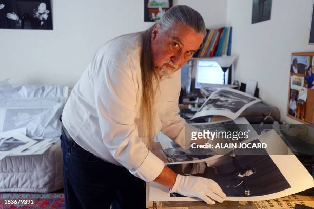 French photographer Hugues Vassal poses on September 27, 2013 in Tours, central France, with one of the many photo portraits he took of late popular...