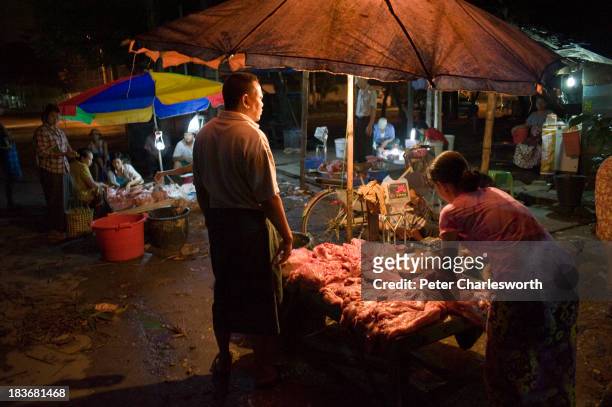 Women vendors sell meat from a stall using battery powered lights, in a small streetside market, because there is more often than not a power cut...