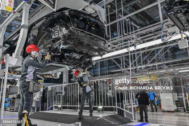 This photo taken on December 8, 2023 shows workers inspecting a car on the production line during a media tour of the "Nissan Intelligent Factory" at...
