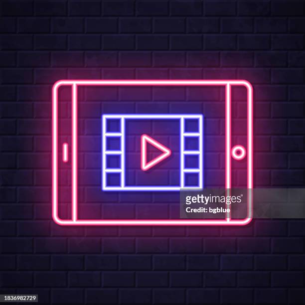 watch video on tablet pc. glowing neon icon on brick wall background - netflix stock illustrations