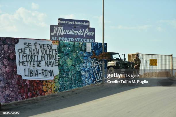 Banner which translates as 'If it is true that you do not want the dead in the sea, create a ship line from Libya to Rome' is displayed at Lampedusa...