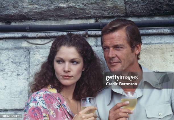 American actress Lois Chiles and British actor Roger Moore holding glasses of wine during a photo call to promote the film 'Moonraker' in Paris,...