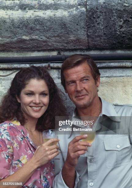American actress Lois Chiles and British actor Roger Moore holding glasses of wine during a photo call to promote the film 'Moonraker' in Paris,...