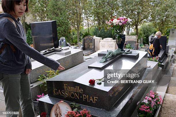 Tourist gestures in front of the grave of French singer Edith Piaf at the Pere Lachaise cemetery in Paris on October 9 on the eve of commemorating...