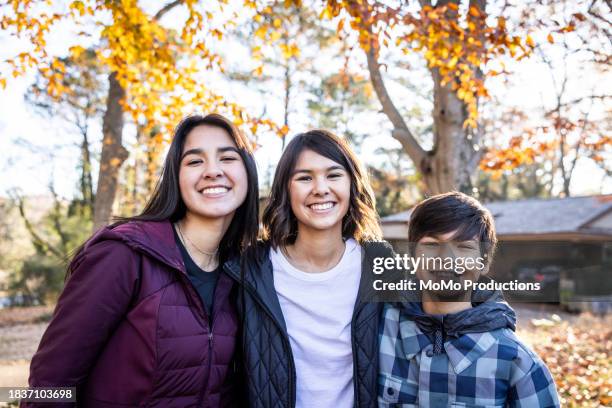 portrait of teenage siblings surrounded by autumn leaves in front yard - 12 17 months stock pictures, royalty-free photos & images