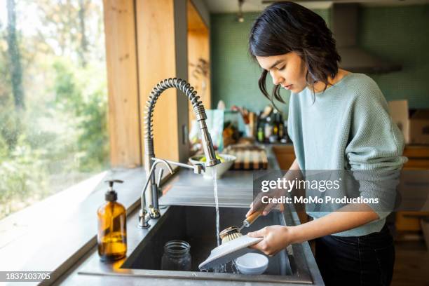teenage girl washing dishes in kitchen - reportage home stock pictures, royalty-free photos & images