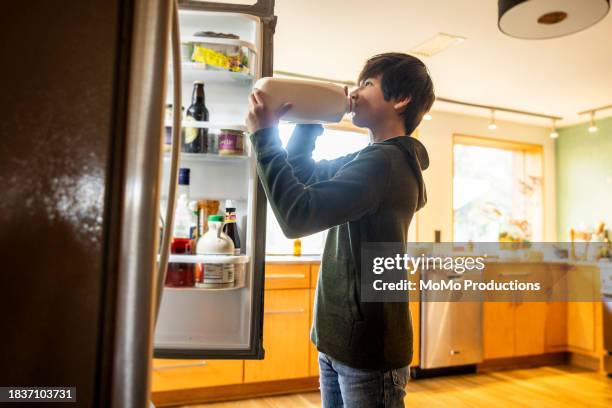 teenage drinking milk out of container in front of refrigerator - open day 13 stock pictures, royalty-free photos & images