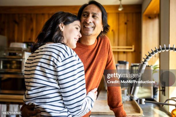 husband and wife embracing in kitchen - lifestyles home stock pictures, royalty-free photos & images