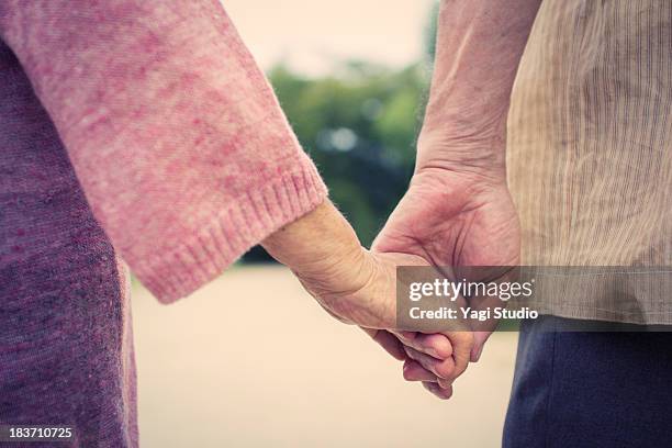 a senior couple is holding hands - japanese ol stockfoto's en -beelden