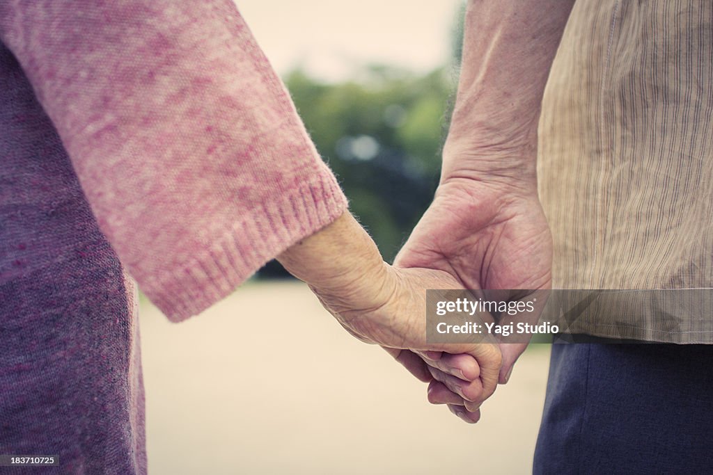 A senior couple is holding hands