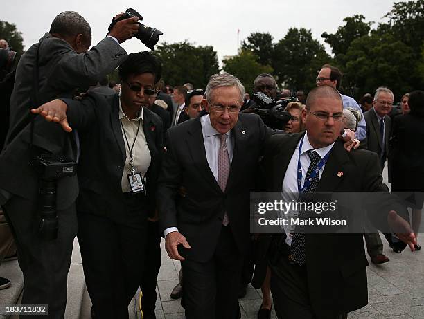 Senate Majority Leader Harry Reid is escorted through a crowd after attending a news conference on the government shutdown at the U.S. Capitol,...