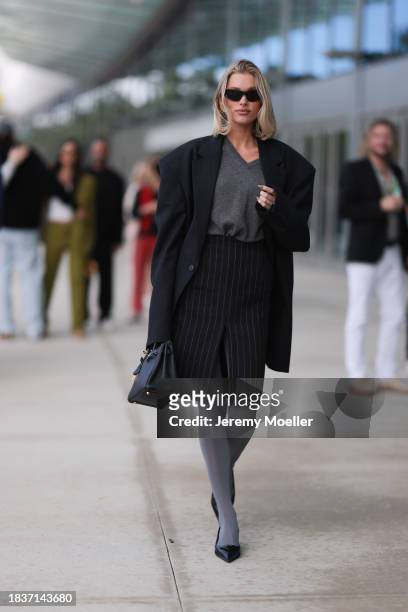 Elsa Hosk seen wearing Balenciaga black sunglasses, gold statement earrings, grey v-neck wool knit jumper, black pinstriped slit midi skirt, black...