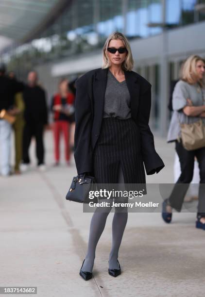 Elsa Hosk seen wearing Balenciaga black sunglasses, gold statement earrings, grey v-neck wool knit jumper, black pinstriped slit midi skirt, black...