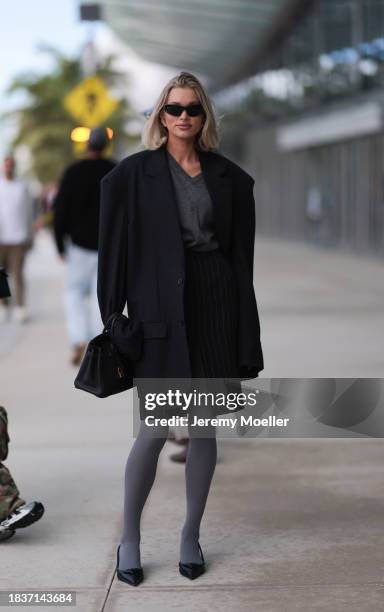 Elsa Hosk seen wearing Balenciaga black sunglasses, gold statement earrings, grey v-neck wool knit jumper, black pinstriped slit midi skirt, black...