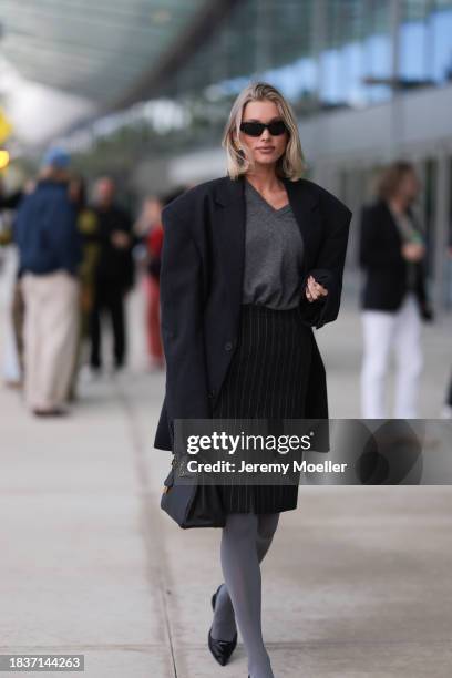 Elsa Hosk seen wearing Balenciaga black sunglasses, gold statement earrings, grey v-neck wool knit jumper, black pinstriped slit midi skirt, black...