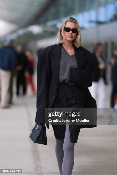 Elsa Hosk seen wearing Balenciaga black sunglasses, gold statement earrings, grey v-neck wool knit jumper, black pinstriped slit midi skirt, black...