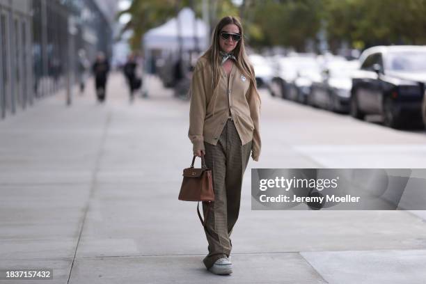 Tara Benmeleh seen wearing black sunglasses, white / black silk pattern small scarf, Comme des Garçons Play beige wool knit cardigan jacket, Hermès...