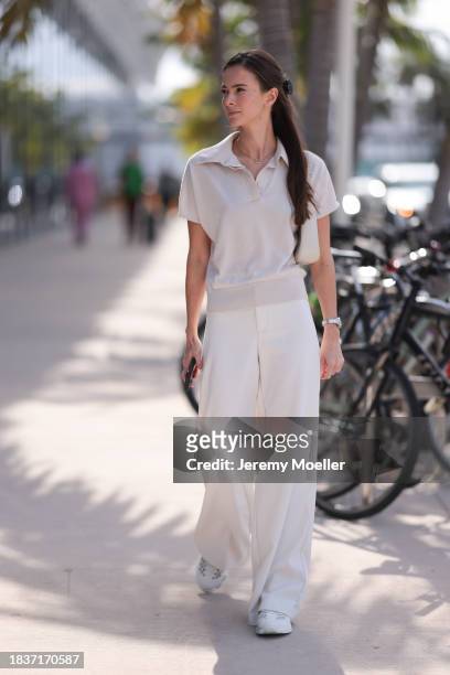 Yana Kotina seen wearing Cartier Love yellow gold chain / necklace, beige cotton polo shirt, white wide leg pants, YSL cream white / beige leather...