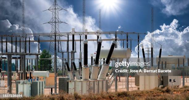 general view of a power distribution power plant over a sunny stormy sky. - electricity transformer stock pictures, royalty-free photos & images